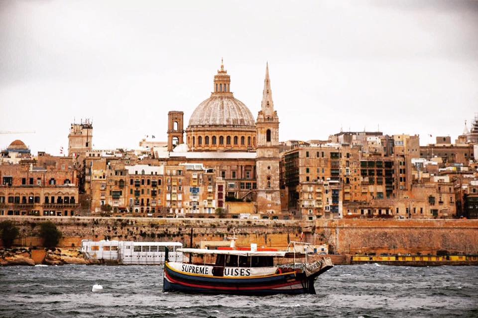 Landscape view of Valletta, Malta with the sea and a traditional boat in front