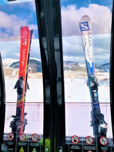 Two sets of skis in a ski cabin with the view of the mountains outside in Roccaraso, a low-budget winter destination in Italy