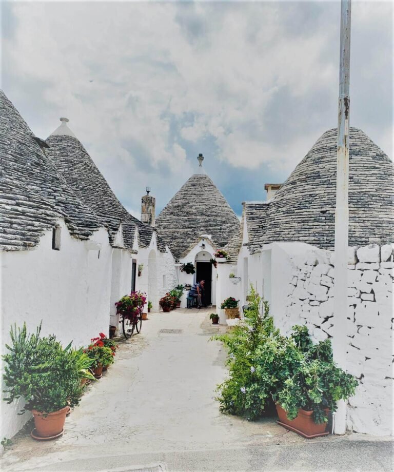 A whitewashed narrow street with conical white houses and plants