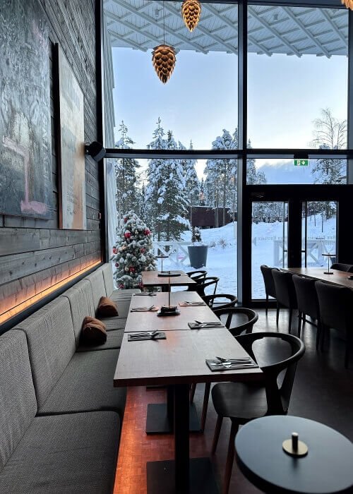 A dinning setting with a high windows showing a winter landscape