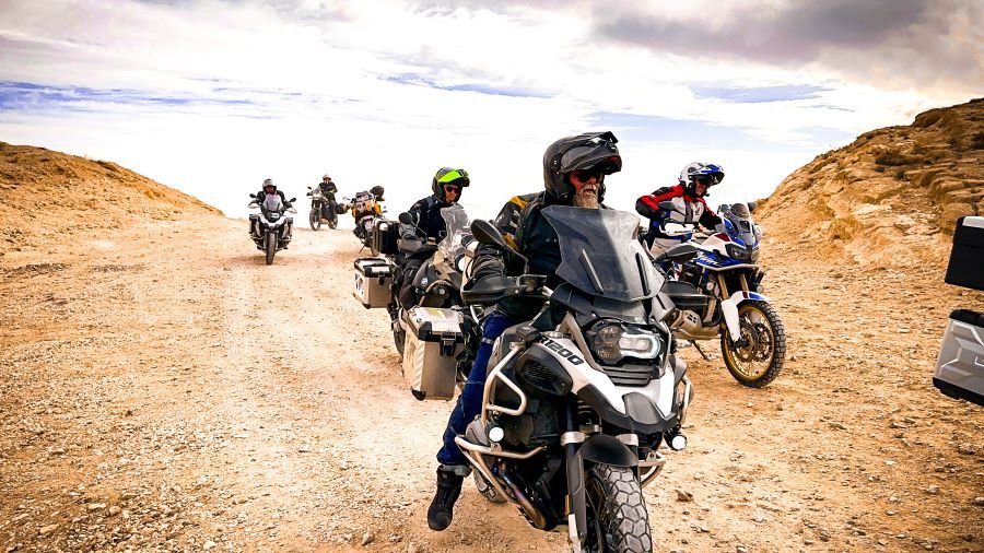 A group of motorcyclists riding in a v-formation on a desert landscape